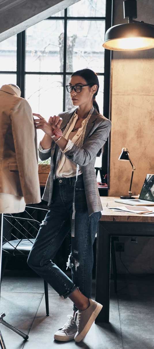 A female clothing designer works on a jacket in a studio